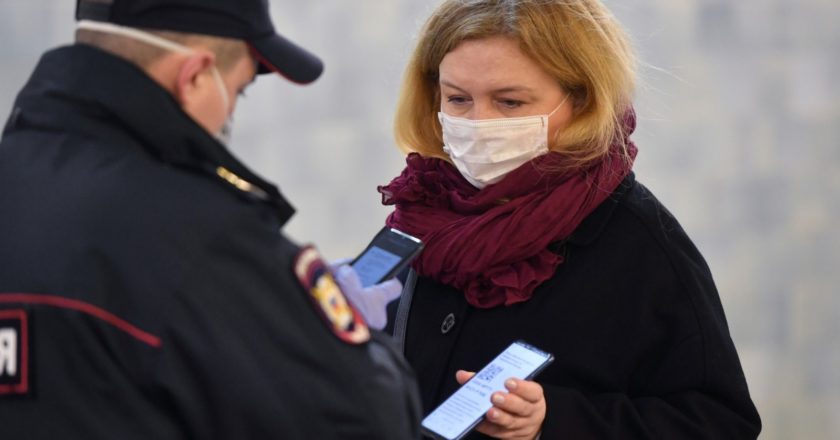 Женщина показывает код своего электронного пропуска на экране смартфона сотруднику полиции. Михаил Воскресенский / РИА Новости