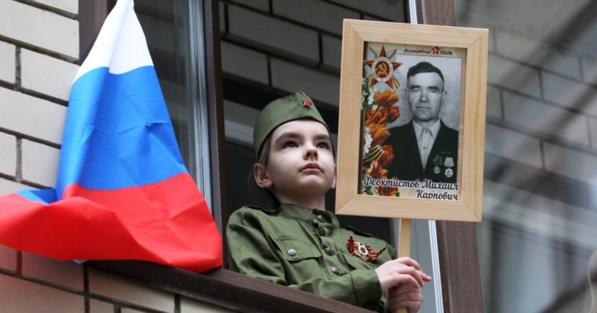 Девочка наблюдает из окна за персональным парадом для ветеранов Великой Отечественной войны, проходящим во дворе жилых домов в Барнауле. Андрей Каспришин / РИА Новости