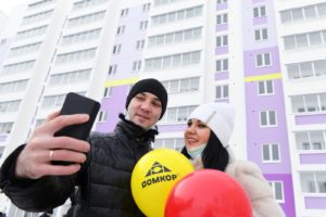 Новоселы фотографируются на фоне нового дома, построенного по программе социальной ипотеки в Набережных Челнах. Квартиры в новом доме получили бюджетники, многодетные и молодые семьи и 92 семьи медицинских работников. Максим Богодвид / РИА Новости